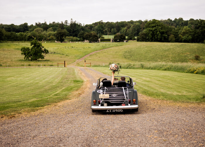 Bride and Groom driving away in vintage car