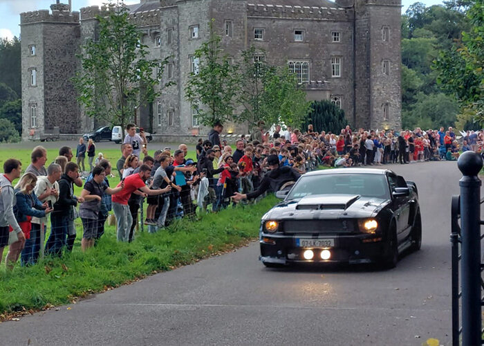 A black sports car driving through Slane Castle for Cannonball event
