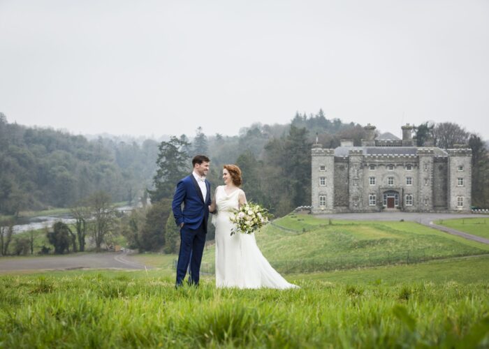 A wedding couple standing on a hill with Slane Castle in the background