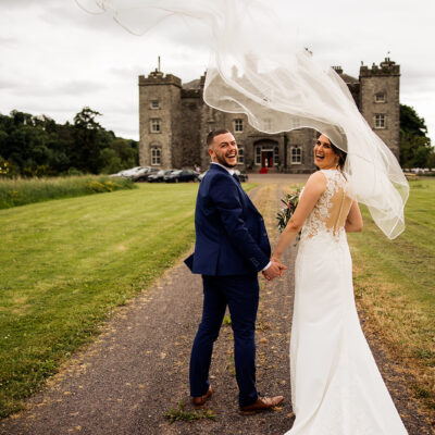 A wedding couple with white veil blowing overhead