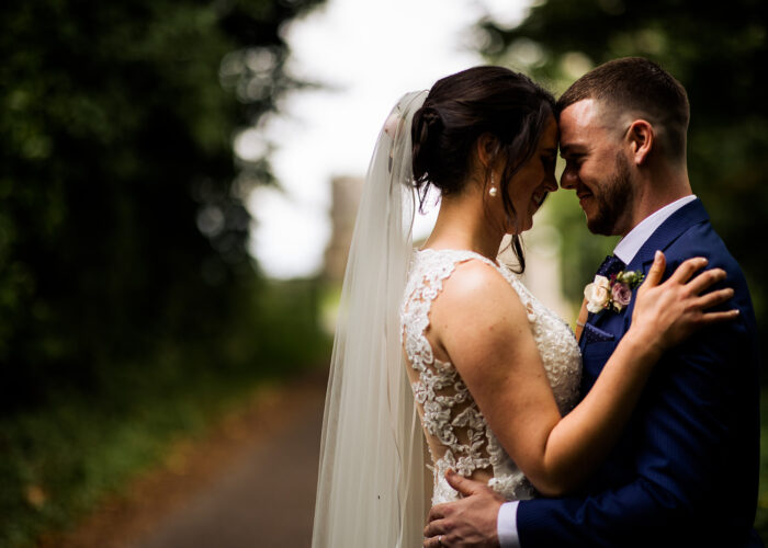 Bride and Groom hugging tree lined walkway