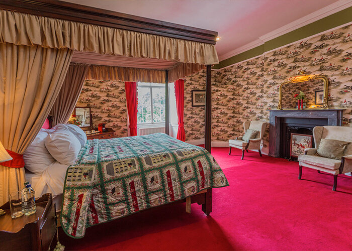 A four poster bed in a room with horse riders on wallpaper