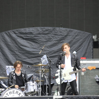 Two people on stage singing and a drummer