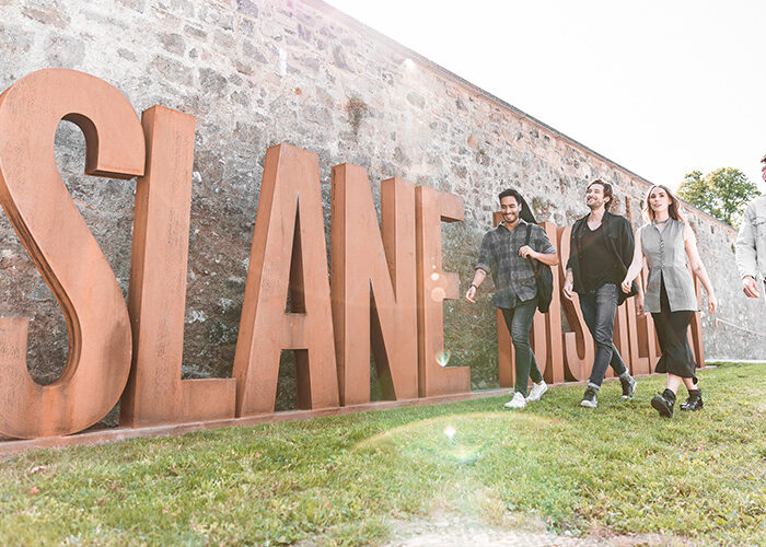 A group of people walking past the Slane Distellery sign