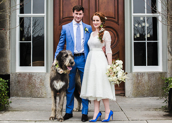 Wedding couple with dog standing outside main door