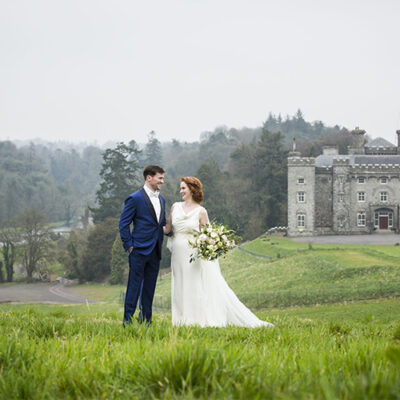 Wedding couple standing on a hill with the castle behind them