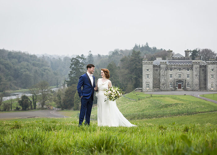 Wedding couple standing on a hill with the castle behind them