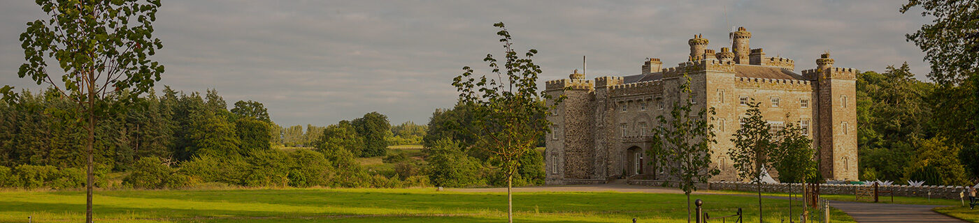 Slane Castle to the side with the sun shining on the fields