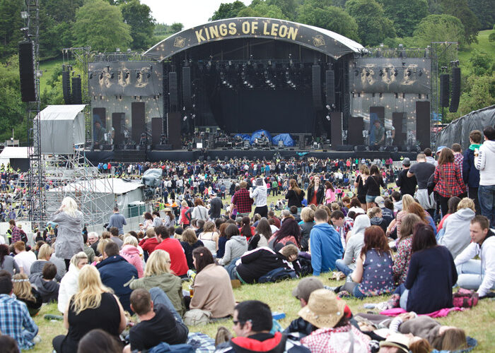 Crowd sitting on hill Kings of Leon on stage