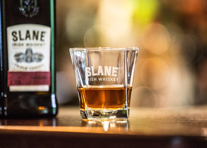 A glass of Slane Whiskey on a bar