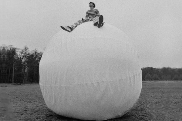 Harry Styles sitting on a big white inflatable